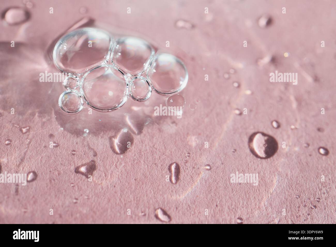 Clear bubbles and water drops creating organic patterns on pink surface Stock Photo