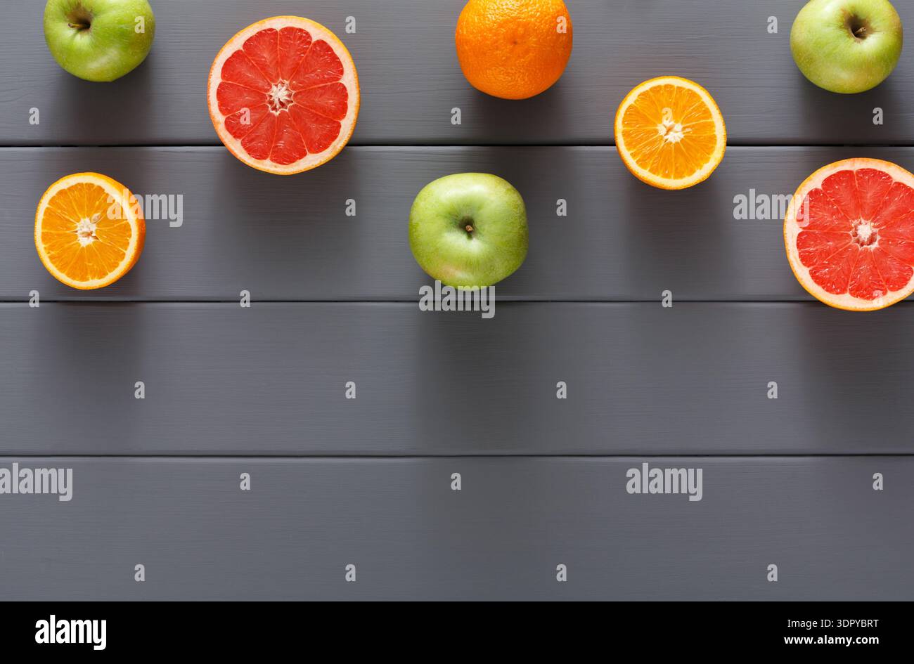 Arrangement of Citrus Fruits and Apples on a Grey Wooden Surface for a Fresh Food Display Stock Photo