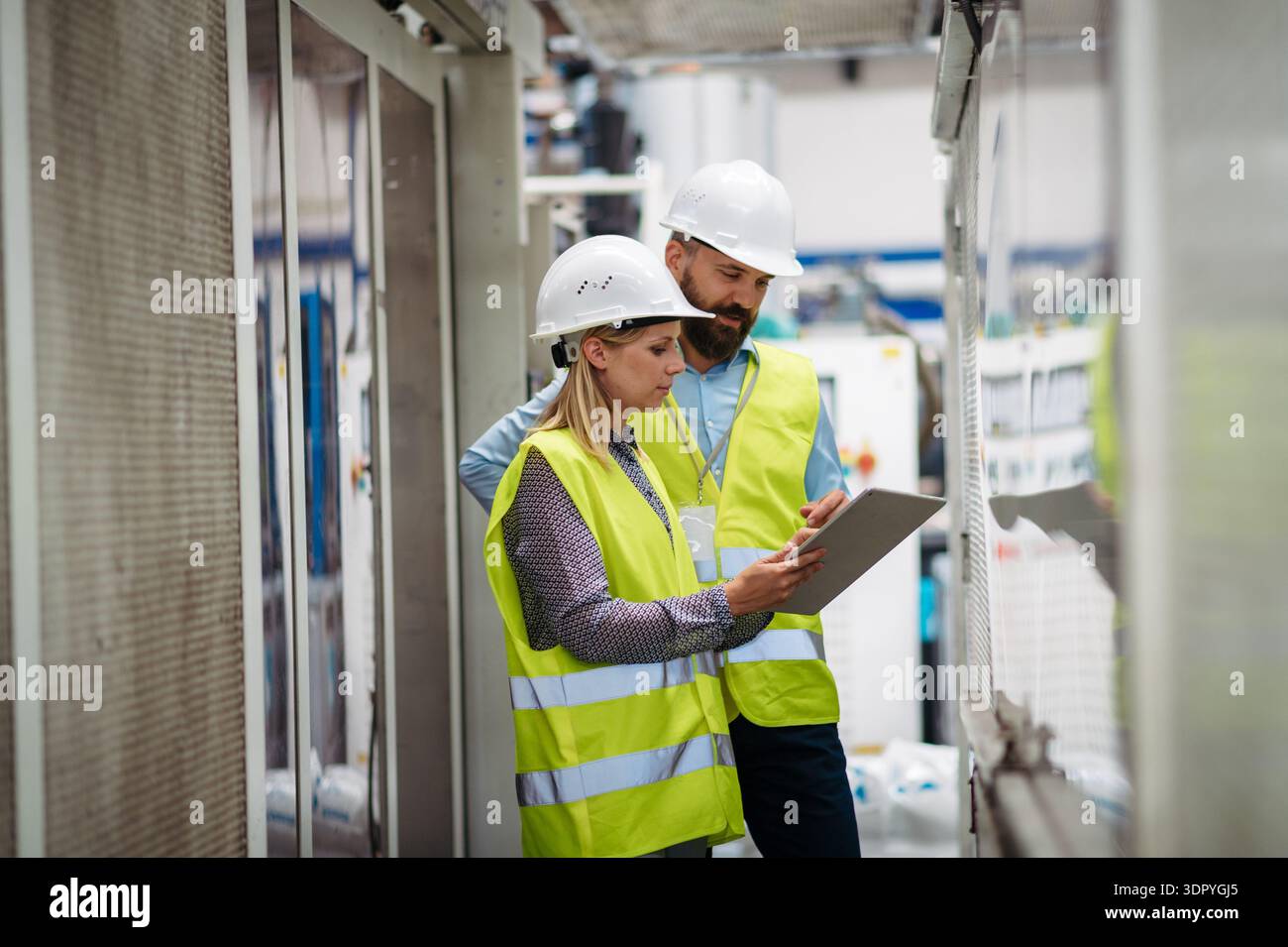 Industrial team analyzing data in high tech manufacturing plant. Stock Photo