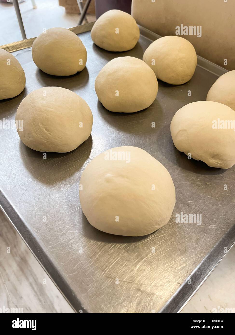 Homemade bread dough balls on a baking tray and dough kneading process in a mixer. - Smartphone Captured Stock Image