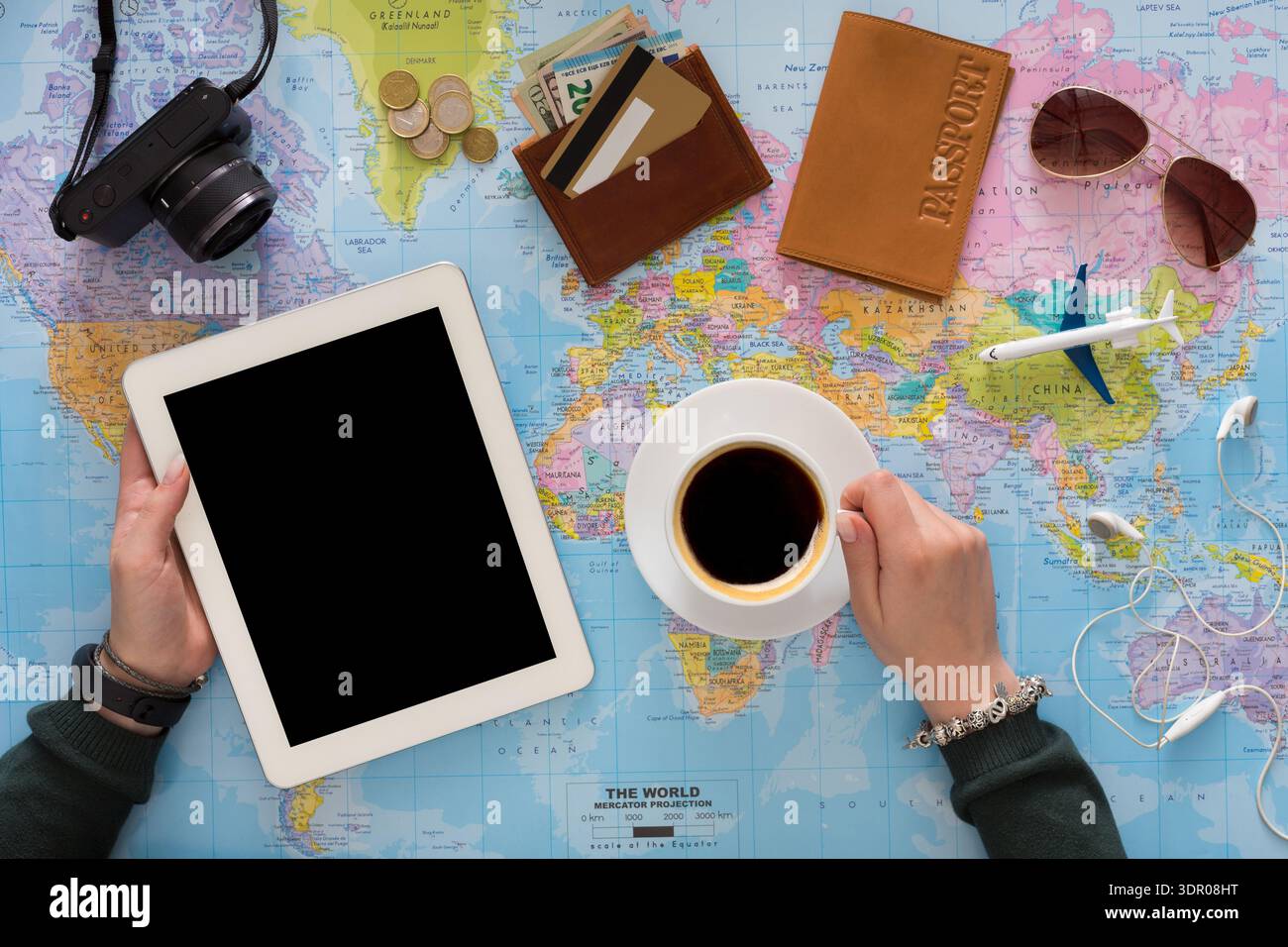 Planning a Trip With a Map, Tablet, Coffee, and Travel Essentials on a Table Stock Photo