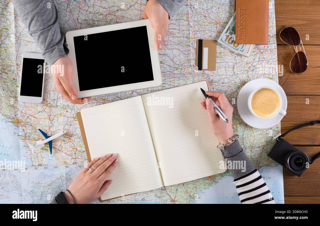 Planning a Trip With Maps, Devices, and Tools on a Table at a Cafe Stock Photo
