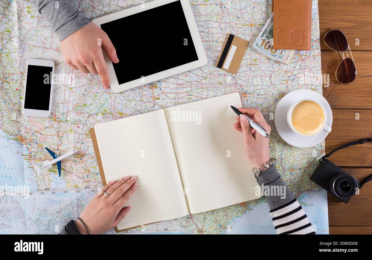 Planning a Trip With Devices, Maps, and Notes in a Cafe Stock Photo