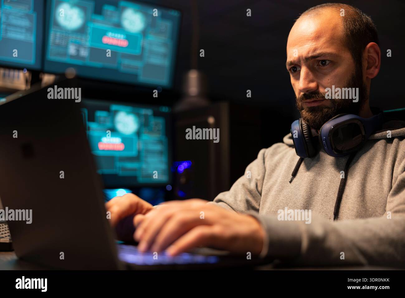 Bearded programmer writing code and developing software for cloud computing and secure connections. Focused freelancer works at night, preventing hacking attempts and resolving surveillance issues. Stock Photo