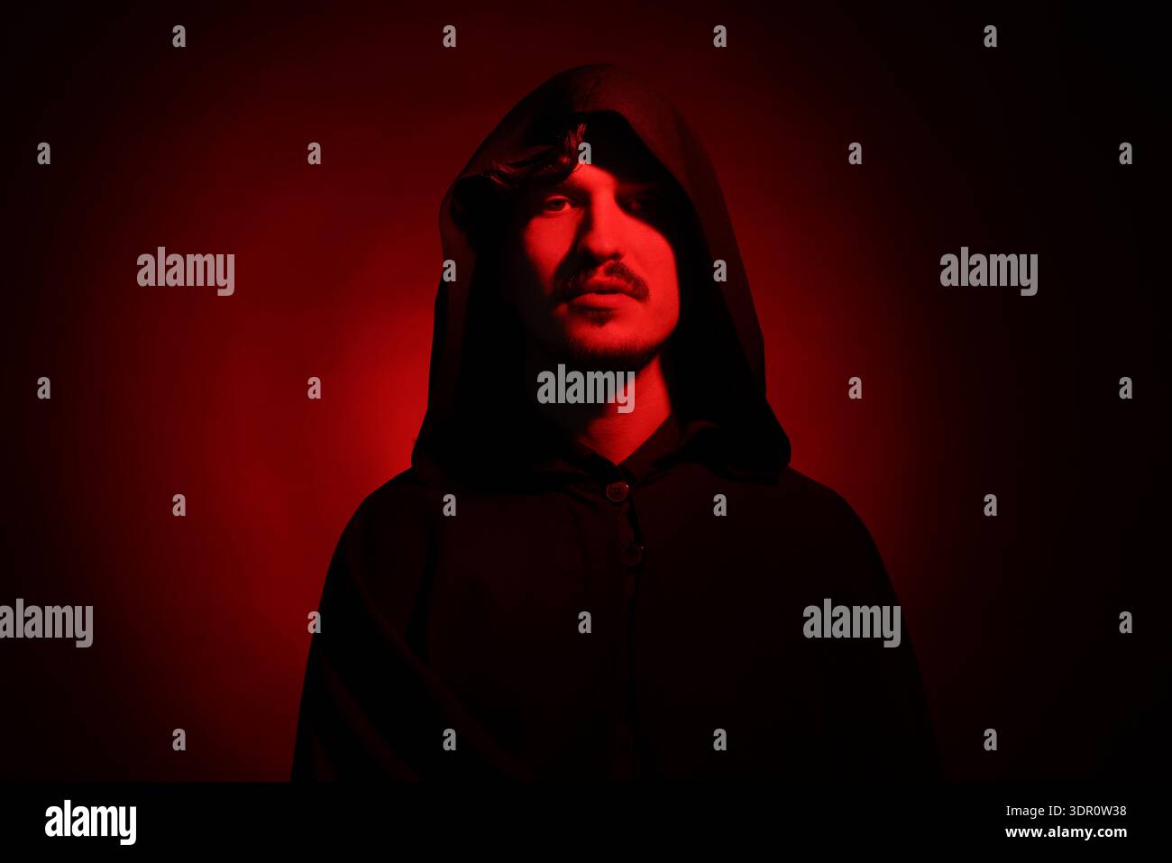 Man in hood on dark background with red light Stock Photo