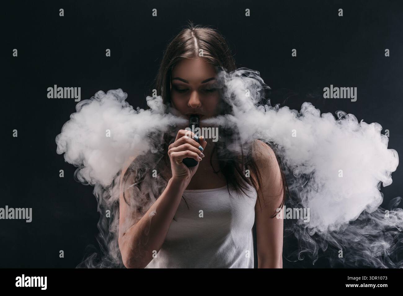 Woman Vaping and Exhaling Clouds of Vapor in a Dark Setting During the  Night Stock Photo