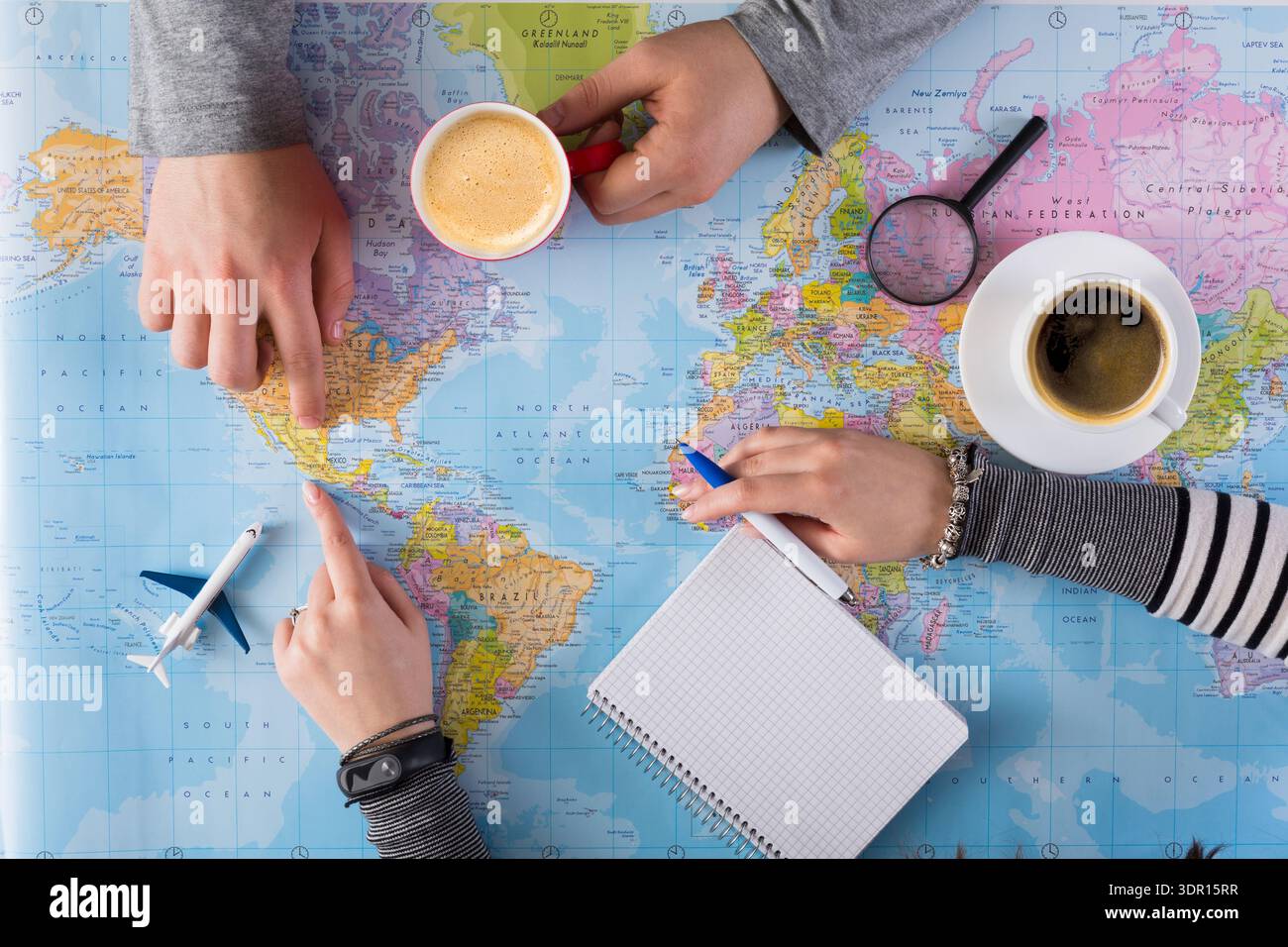 Planning a Trip While Looking at a Map With Coffee and Notepad on the Table Stock Photo