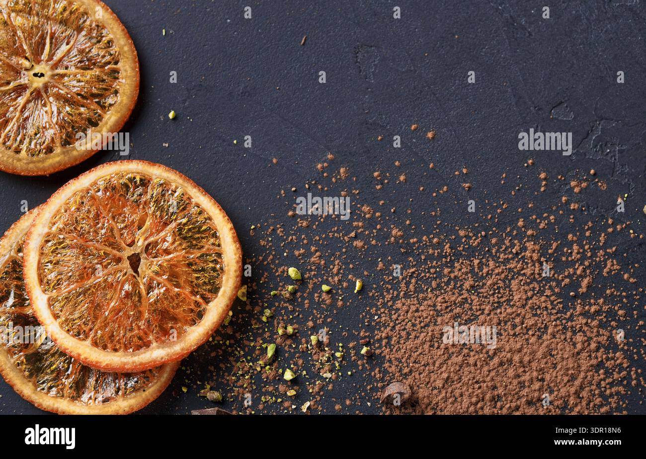 Dried Orange Slices and Cocoa Powder Placed on Dark Surface in Kitchen Setting Stock Photo