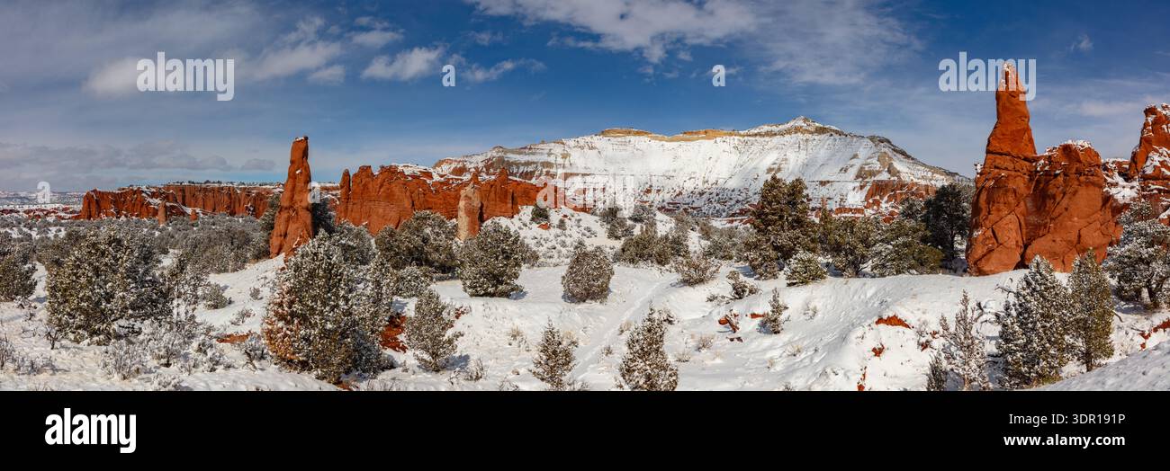 This winter panorama features fresh snow blanketing Kodachrome Basin State Park, Utah, as the vibrant red sandstone spires extend toward the blue sky. Stock Photo