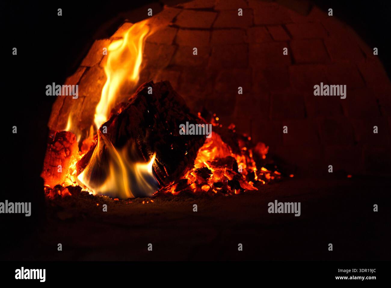 Flames Burn Brightly Inside a Stone Oven at Night Stock Photo
