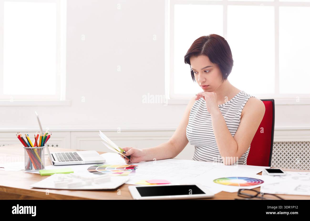 Young Woman Working on Design Project at Desk With Laptop and Color Samples Stock Photo