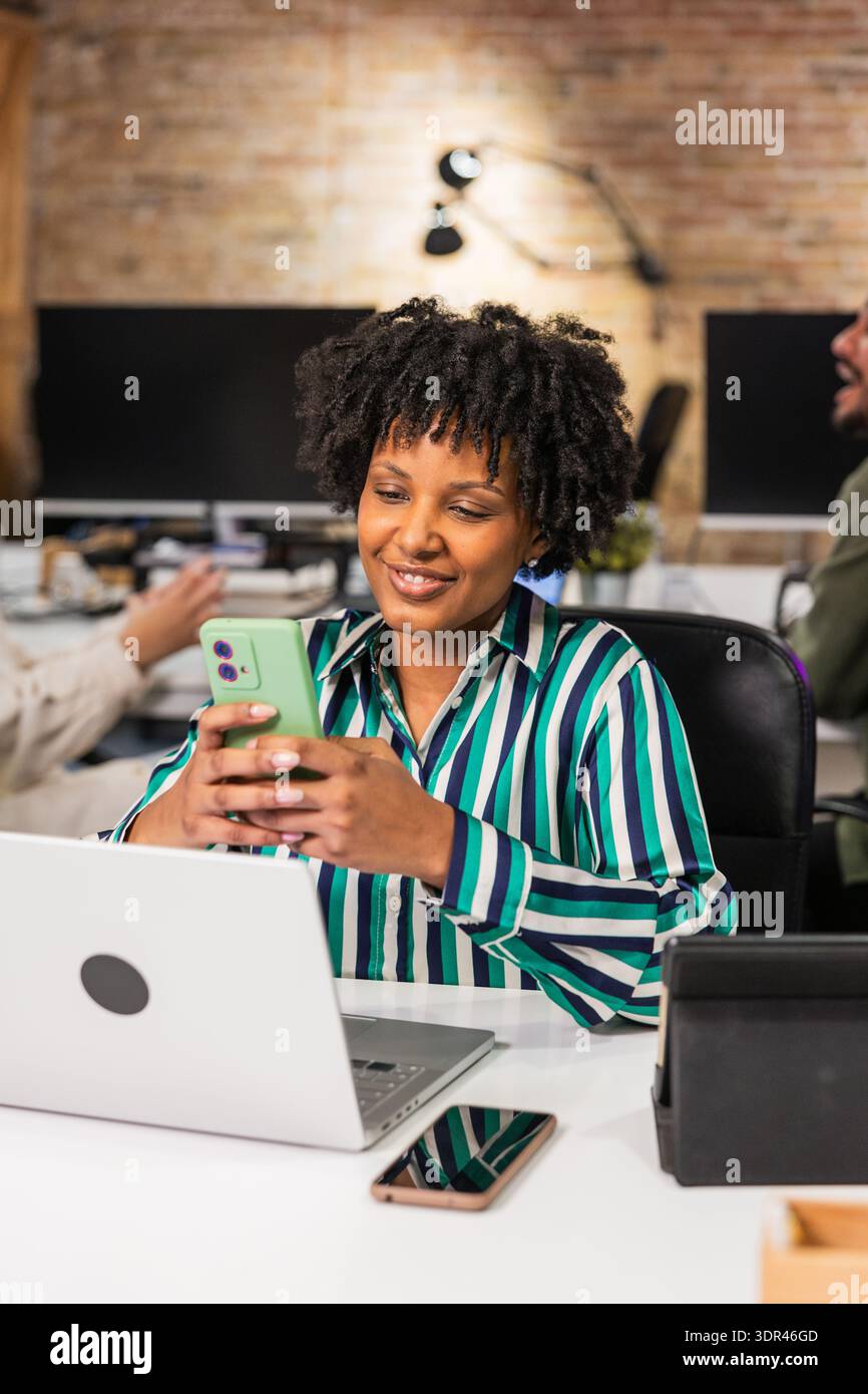 Manager using smartphone and laptop at work in modern office Stock Photo