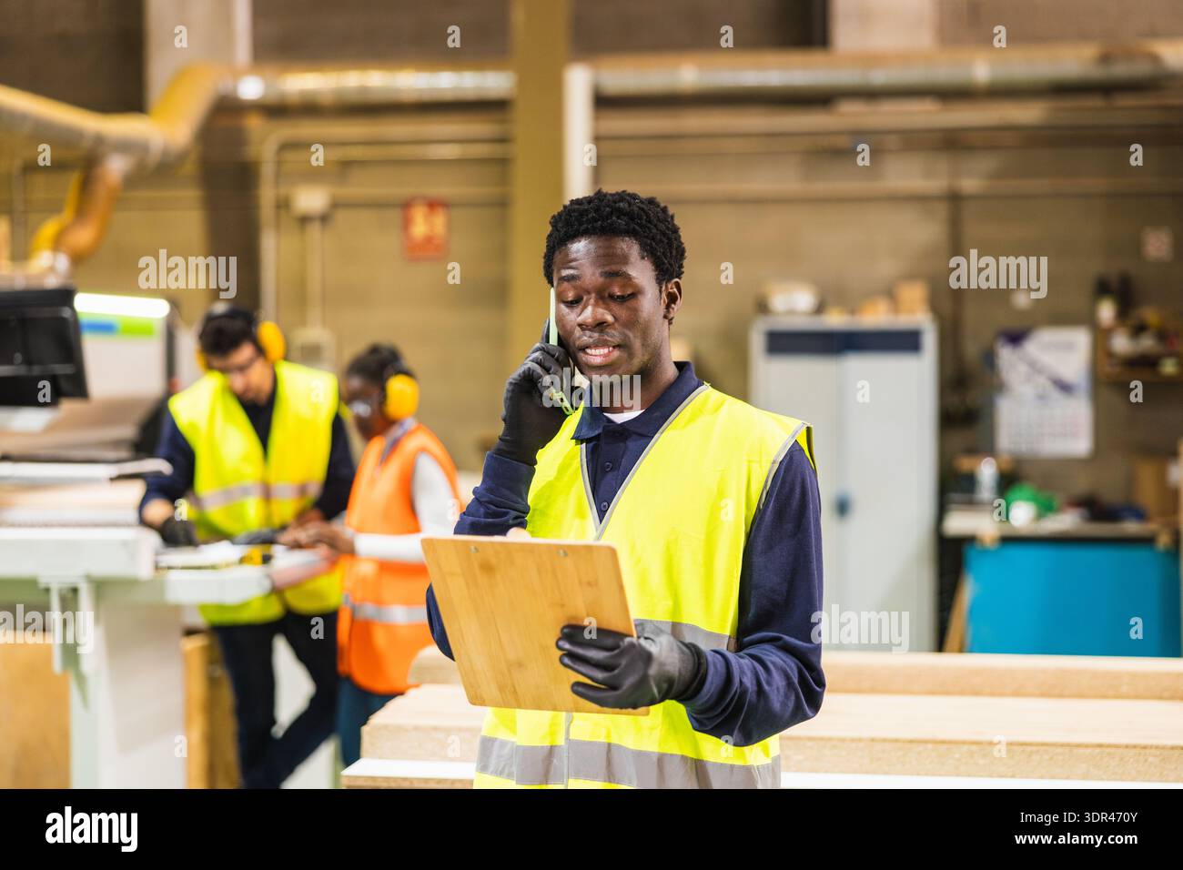 Worker having phone call in lumberyard warehouse Stock Photo