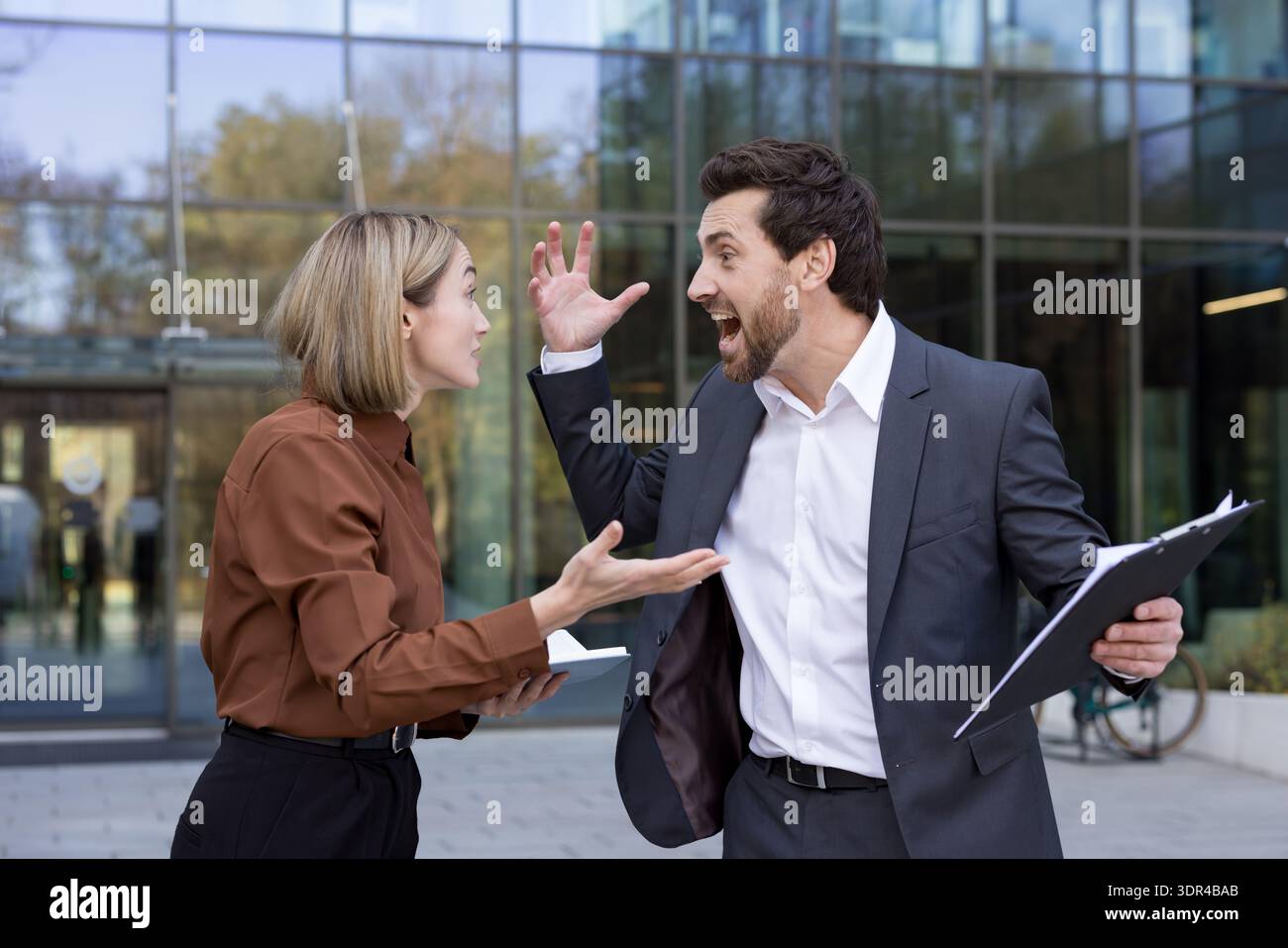 Businesspeople having a heated argument outside modern office building ...