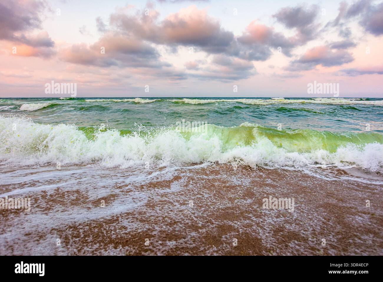 stormy weather on the sandy beach. dramatic sky over the black sea. moody summer landscape in morning light. green waves crashing the shore. majestic Stock Photo