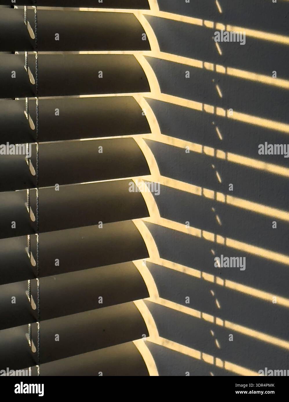Sunshine streaming through Venetian Blinds in a domestic kitchen creating shadows on a wall, Worcestershire, England. Stock Photo