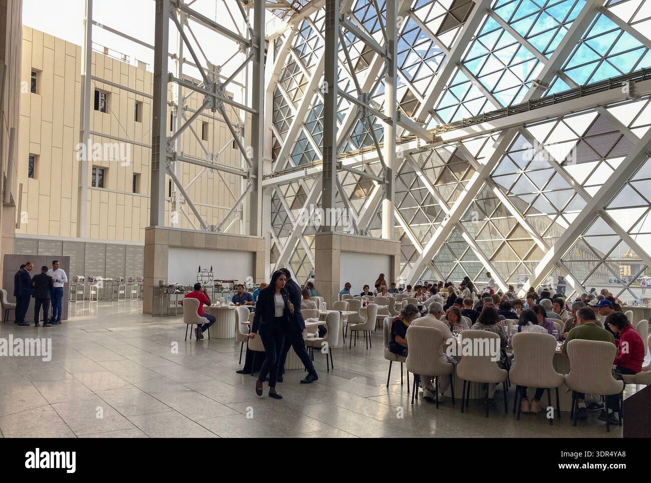 Visitors to the Grand Egyptian Museum in Giza, Cairo, Egypt, enjoy lunch in one of the restaurants in the rear atrium bathed in natural light. - Smartphone Captured Stock Image