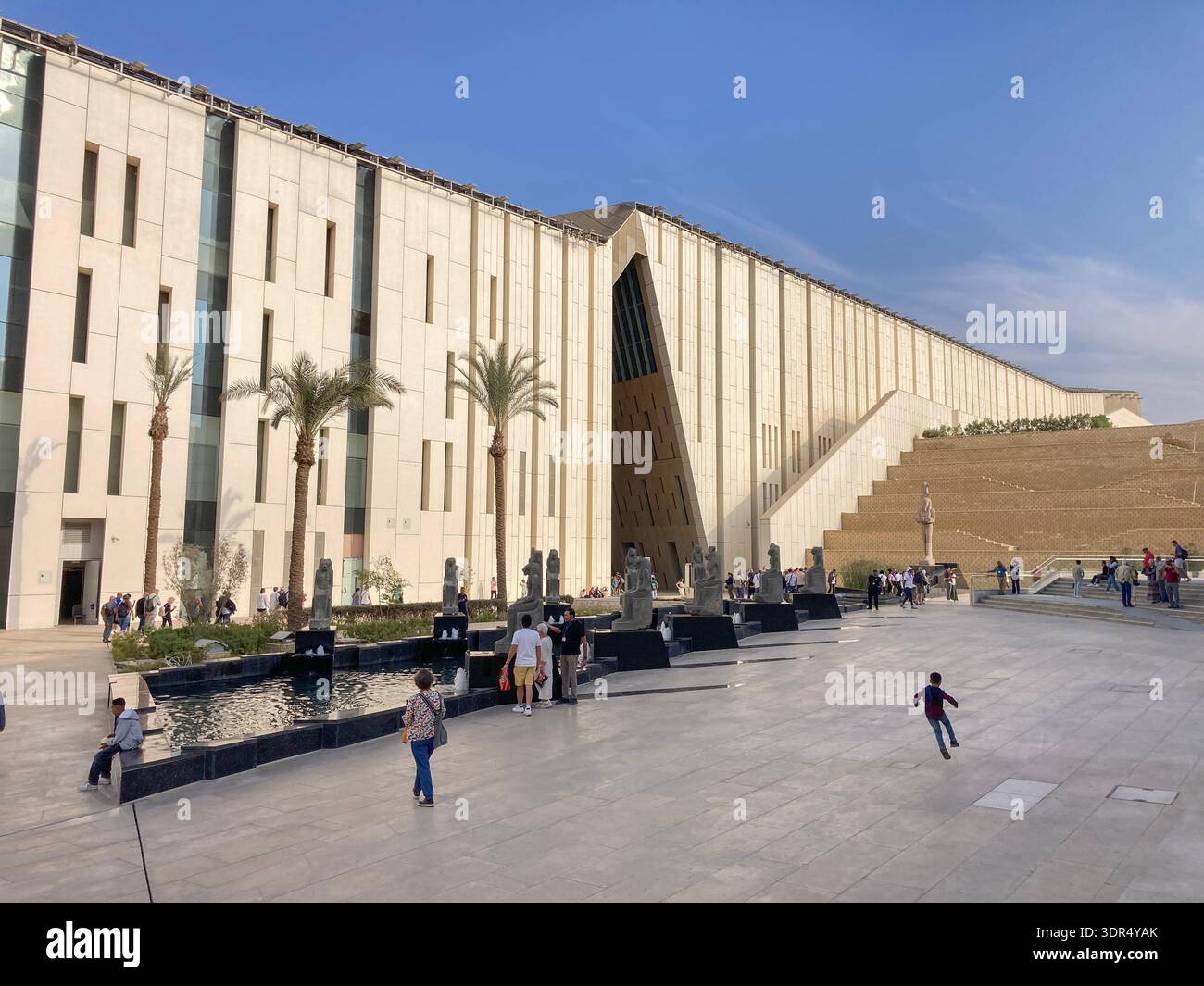 The Grand Egyptian Museum rear entrance seen across a plaza and its fountains from the Khufu's Boats Museum in Giza, near Cairo, Egypt. - Smartphone Captured Stock Image