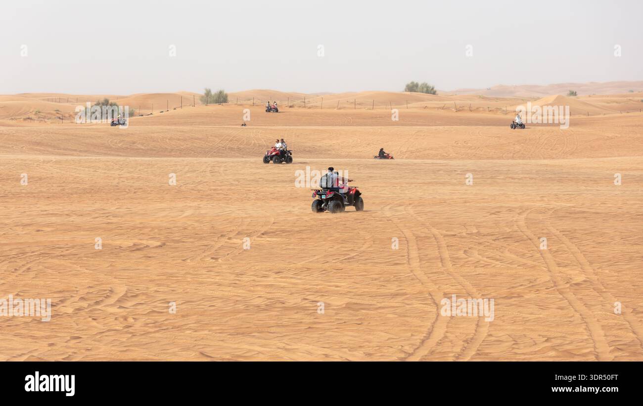 Dubai, United Arab Emirates-March 9, 2025: Essence of Arabian desert with multiple quad bikes moving across vast sand dunes. Outdoor adventure concept Stock Photo