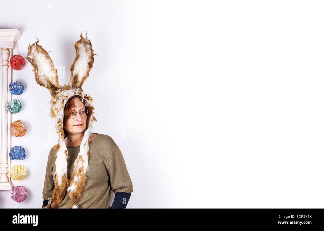 Sstudio portrait of a middle aged woman wearing handmade felted bunny hat with long ears standing against white background. Copy space Stock Photo