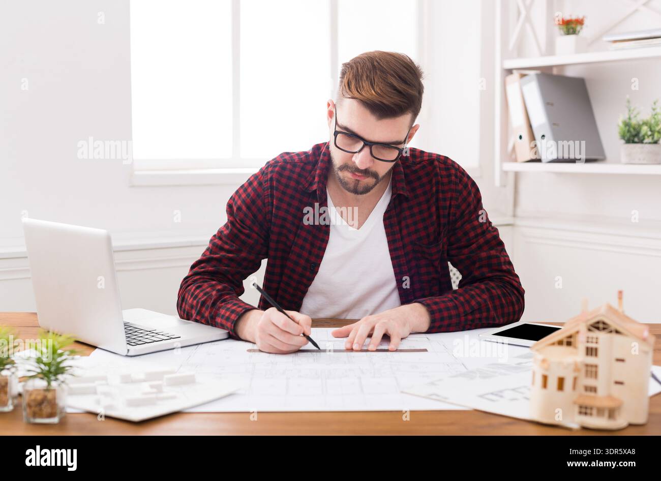 Designer Works on Project Plans in a Modern Office Setting During Daytime Hours Stock Photo