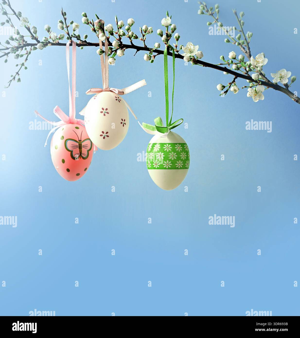 Branches of cherry blossoms are decorated with Easter eggs against blue sky. Holiday concept. Religious holiday Easter. Nature. Spring background. Stock Photo