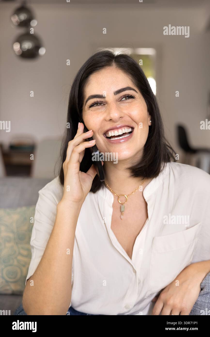 Cheerful positive young Latin phone user woman talking on cell Stock Photo