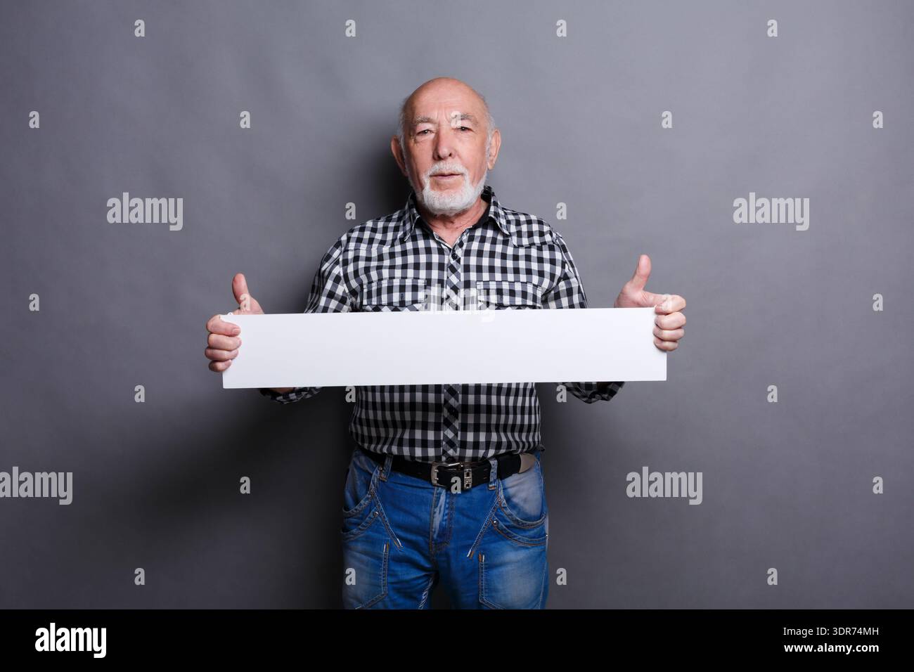 Senior Man Holds Blank Sign With Thumbs up in Studio Setting During Daytime Lighting Stock Photo