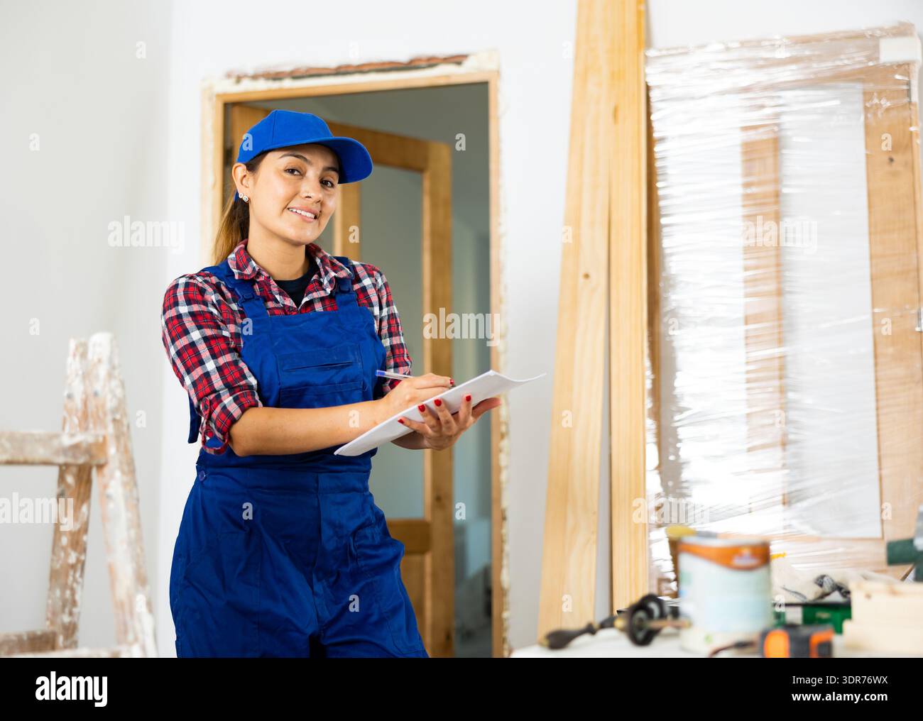 Cheerful woman engineer checking documents in new apartment Stock Photo