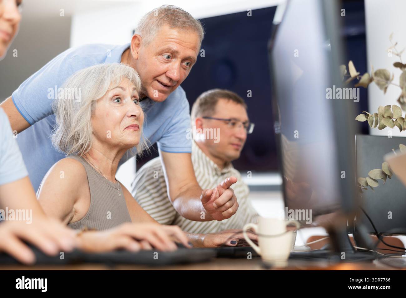 Older mentor explaining something to elderly woman during computer class Stock Photo