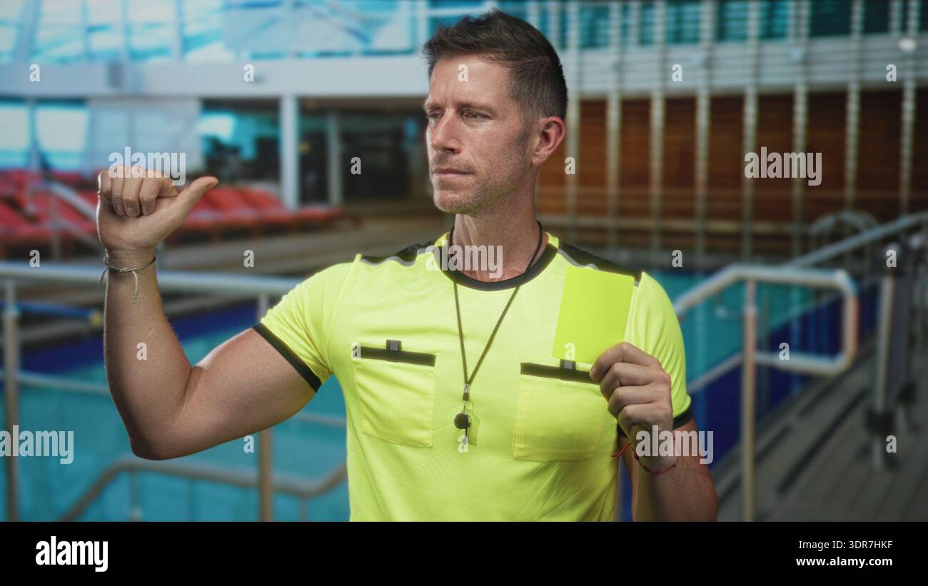 Man referee holding yellow card and thumb to chest, wearing neon shirt ...