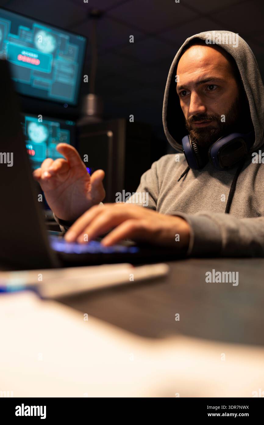 White man analyzing software solutions, coding and planning secure digital workflows. Caucasian male coder wearing sweatshirt hoodie, types steadily while reviewing technical interfaces on laptop. Stock Photo