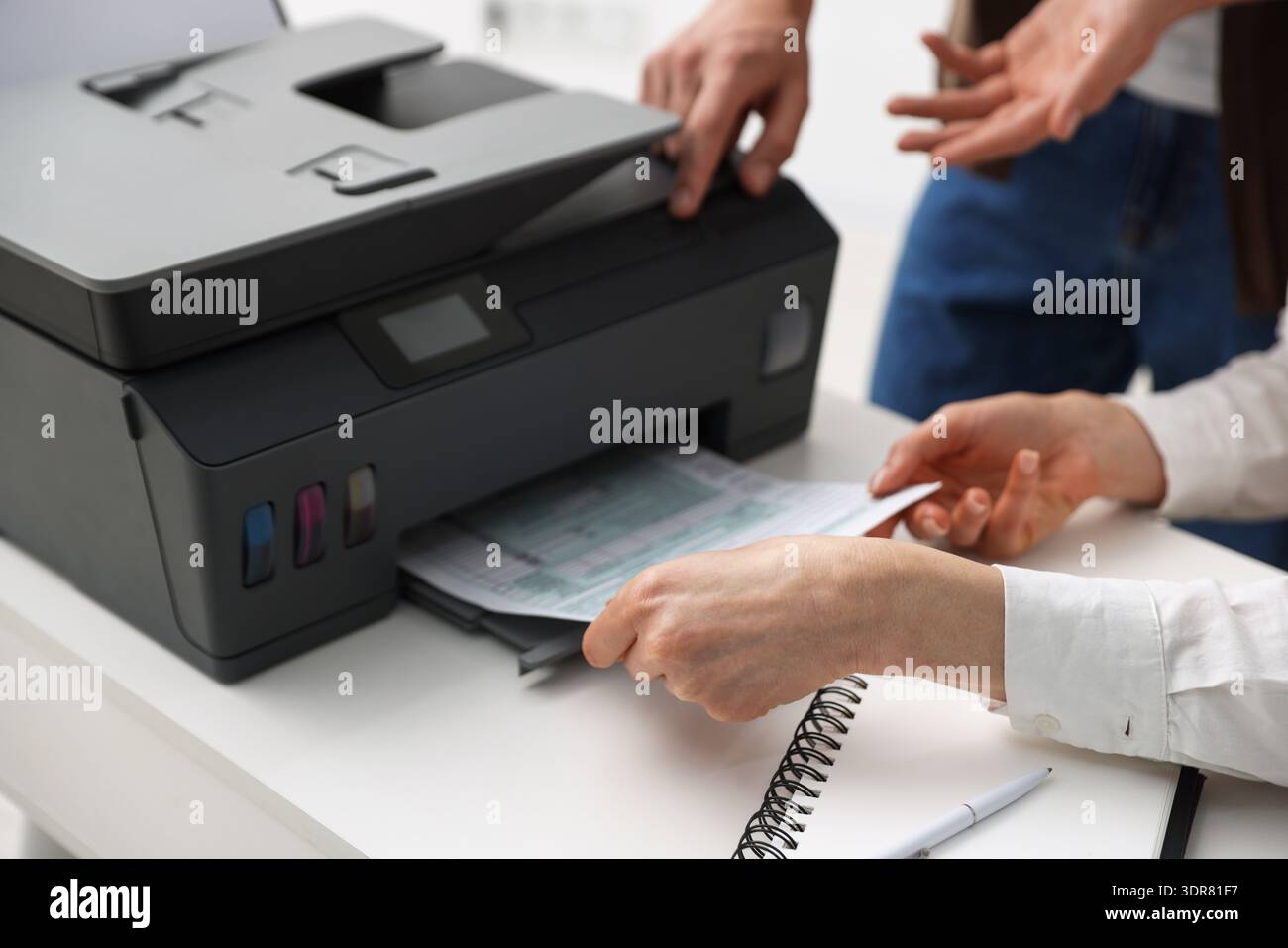 Office workers using printer at white desk indoors, closeup Stock Photo