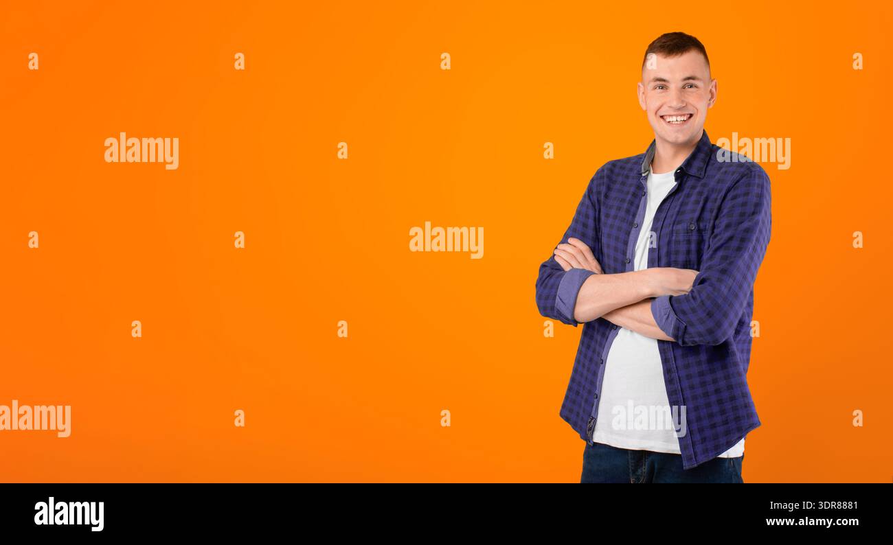 Cheerful Young Man Standing Crossing Hands Posing Over Blue Background Stock Photo