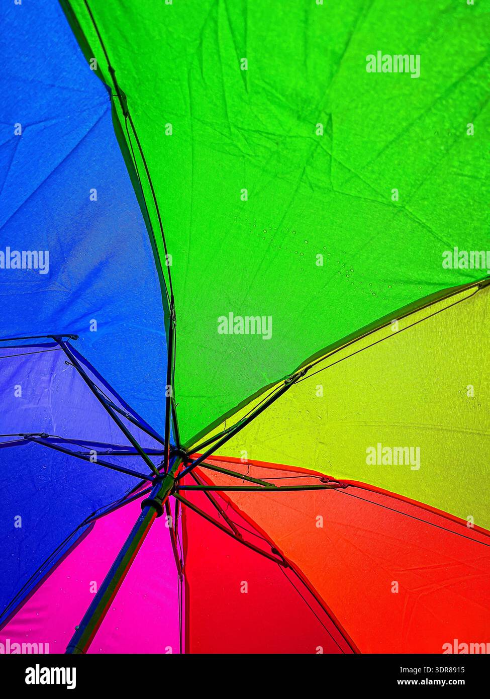 Rainbow umbrella sprinkled with raindrops as seen by the holder. - Smartphone Captured Stock Image