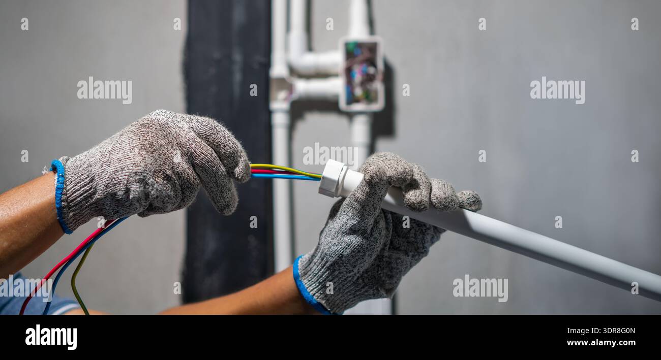 Electrician pulling wire through PVC Conduit from solar inverter  system. Stock Photo