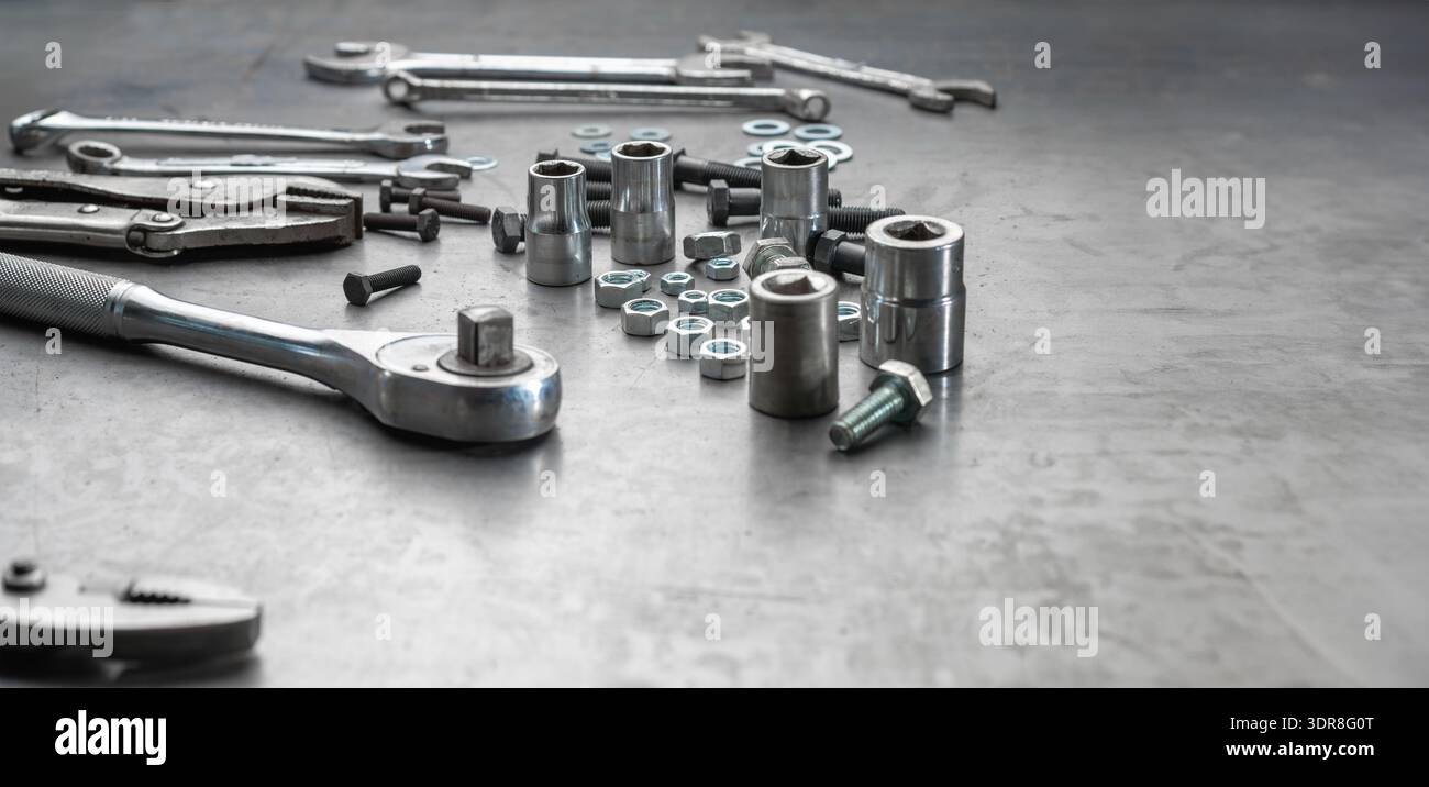 Open end wrench , socket wrench and nuts on steel work bench Stock Photo