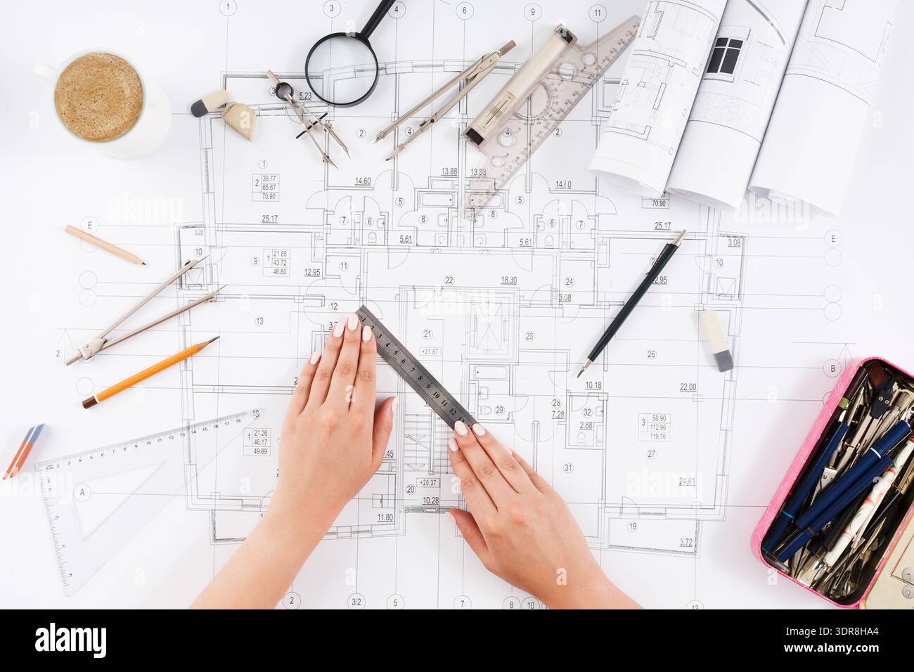 Hands Working on Architectural Plans With Various Tools and Materials on the Table Stock Photo