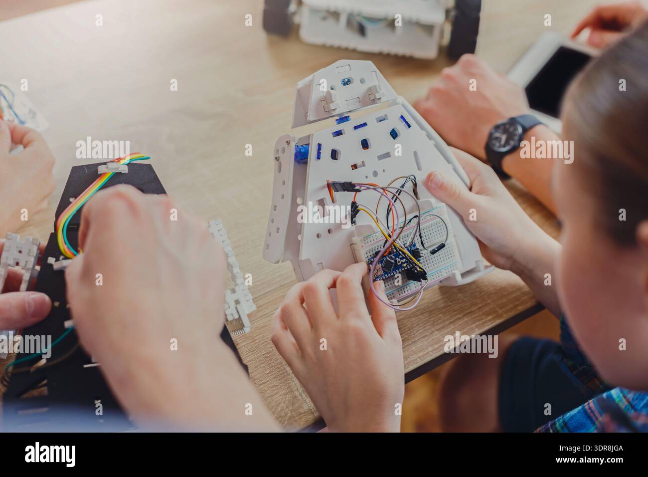 Participants Work on Building a Robot at a Workshop in a Classroom Setting During the Day Stock Photo