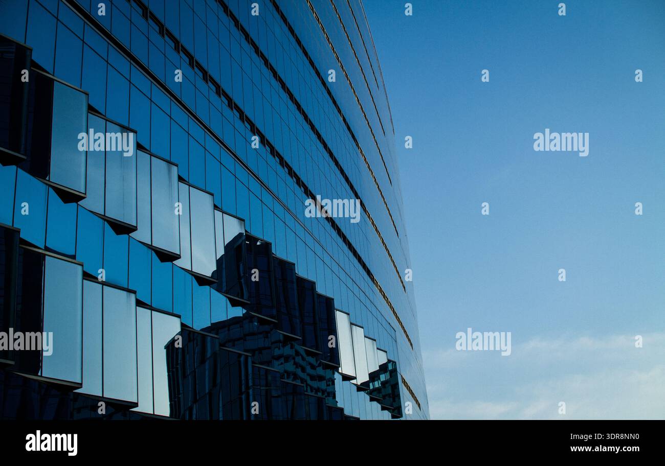 Modern glass building with dramatic angular facade against deep blue ...