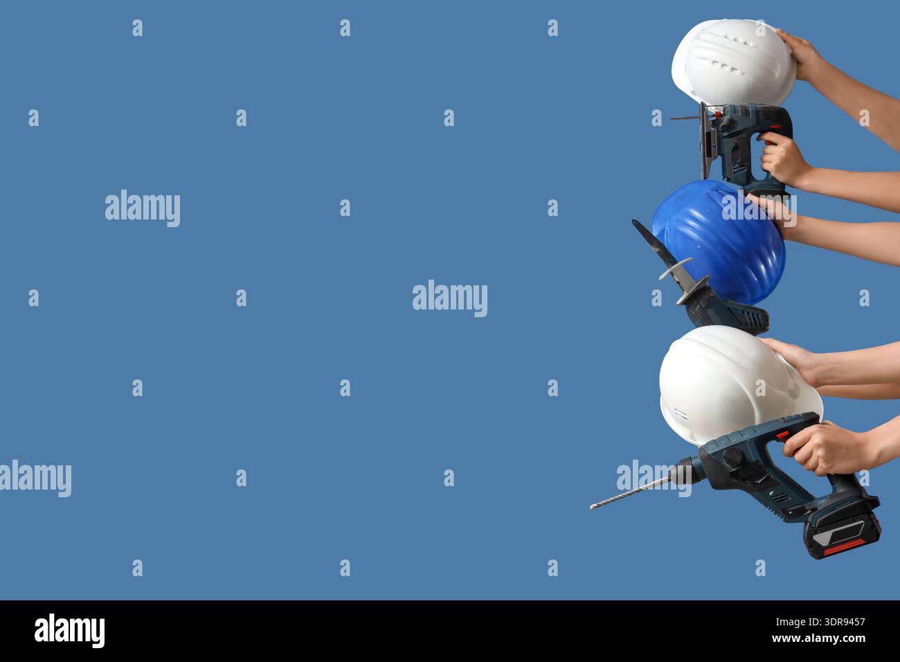 Hands with hardhats and construction tools on blue background Stock Photo