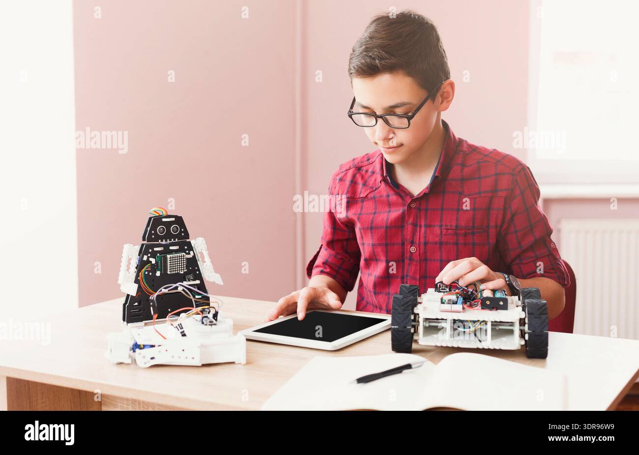 Student Works on Robotics Project and Uses Tablet for Programming and Control Stock Photo