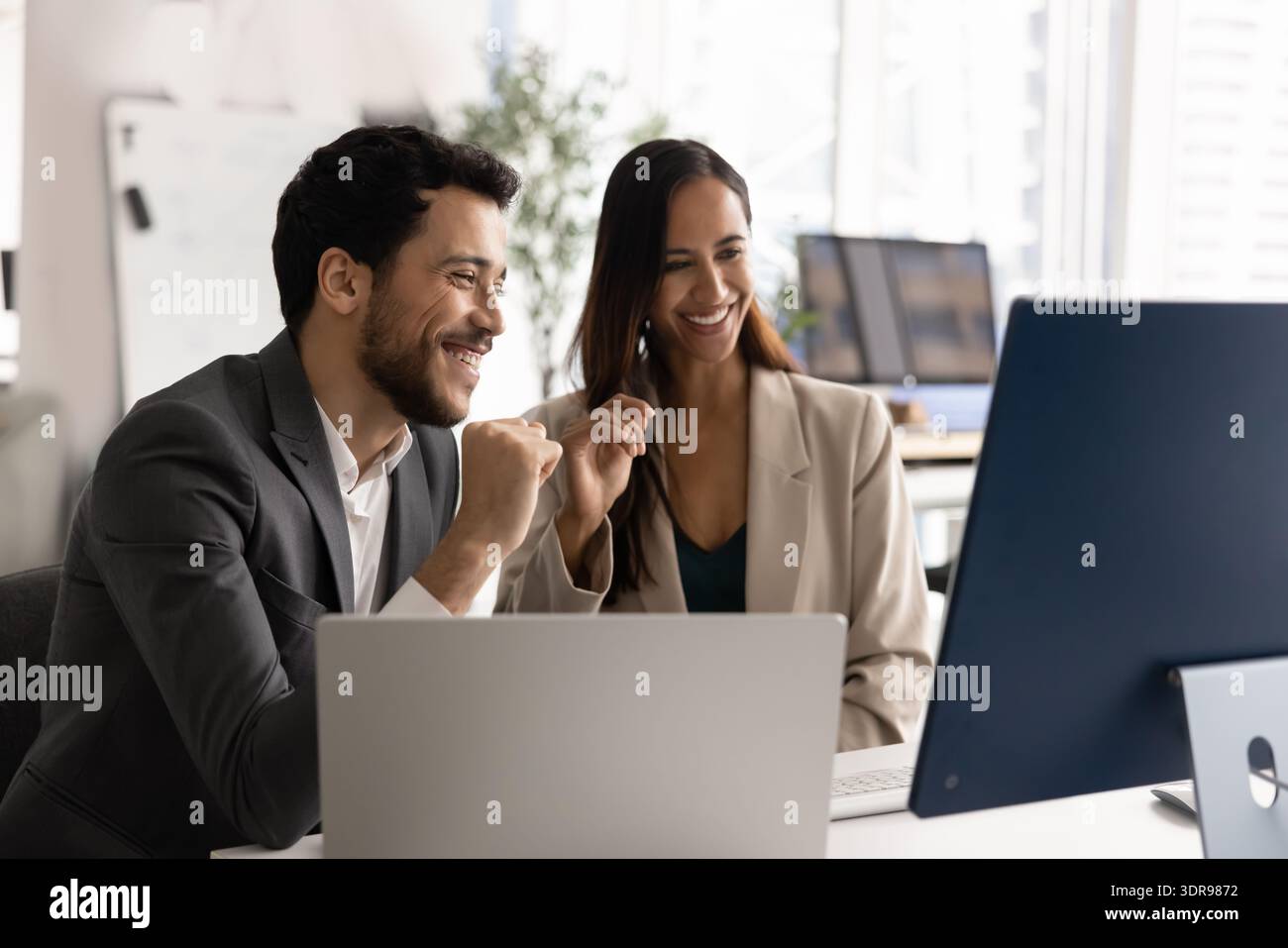 Team of two professionals collaborating in modern office using computer Stock Photo