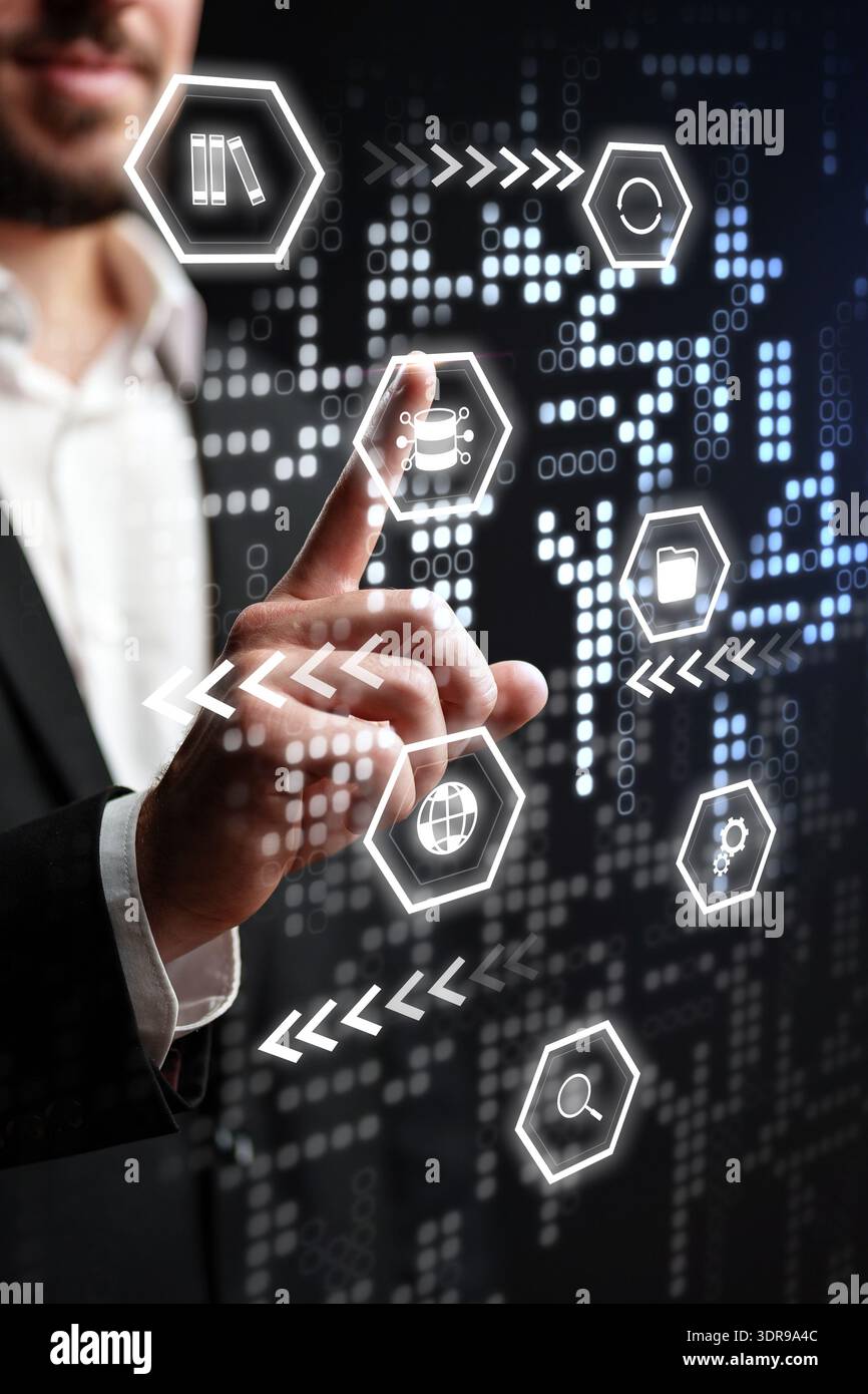 Man interacts with digital interface showing various icons and data patterns in a tech setting Stock Photo