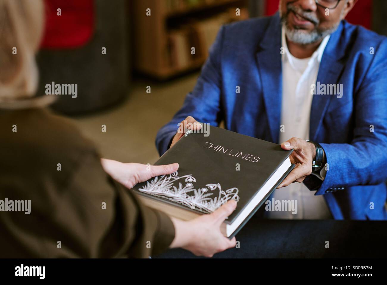 Middle Aged Male Author Handing Book to Middle Aged Woman Stock Photo