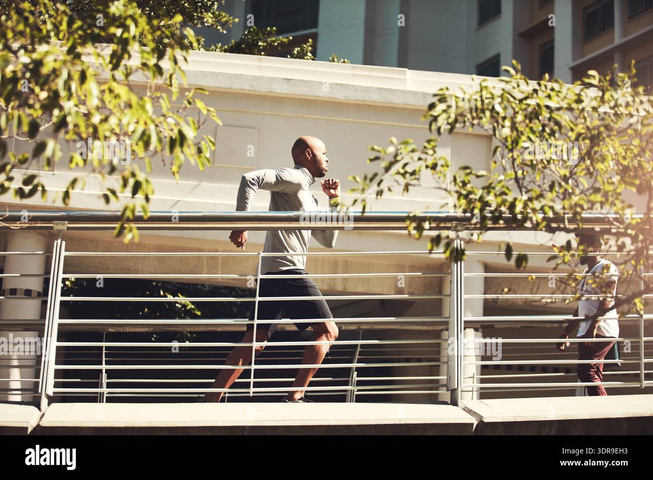 Athlete, black man and running for fitness in city for exercise, training and physical activity. Serious, male person and bridge with speed challenge Stock Photo