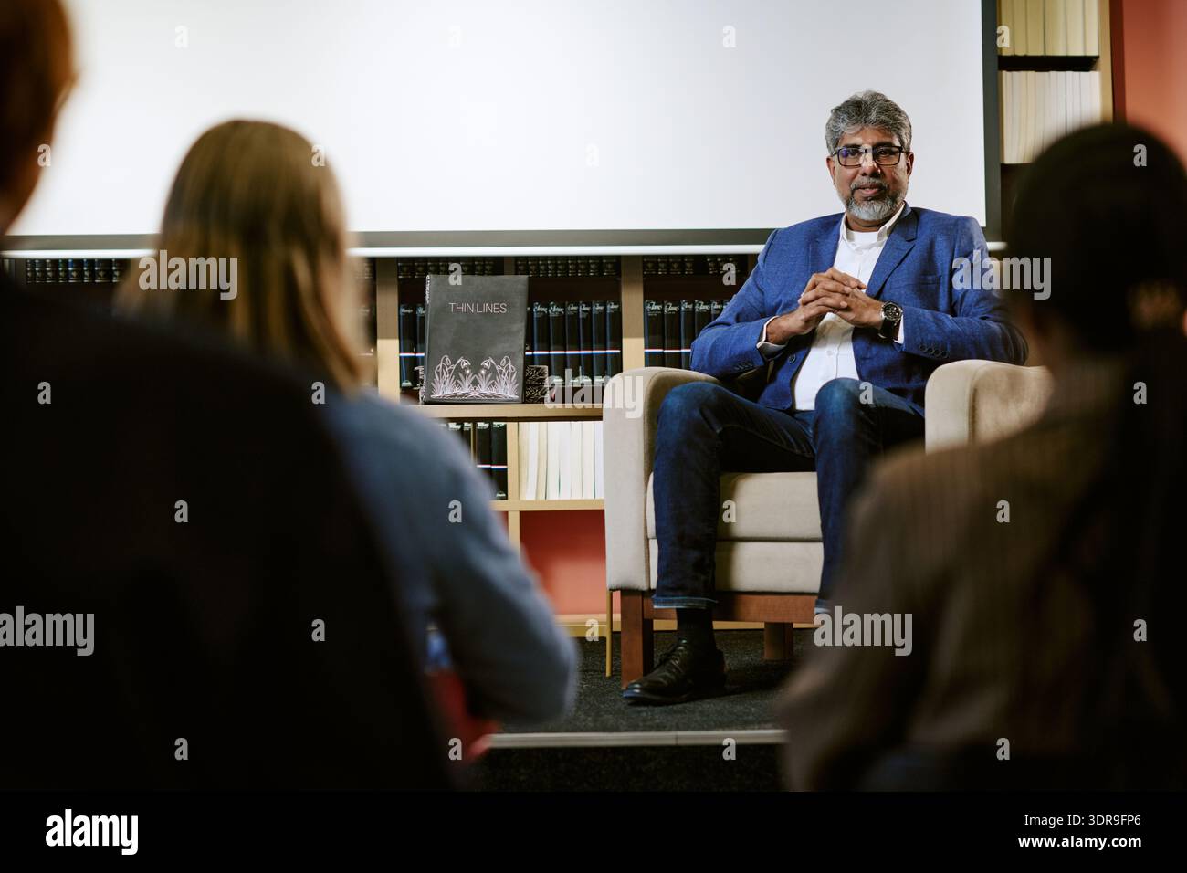 Middle Aged Man Giving Presentation to Diverse Audience in Library Stock Photo