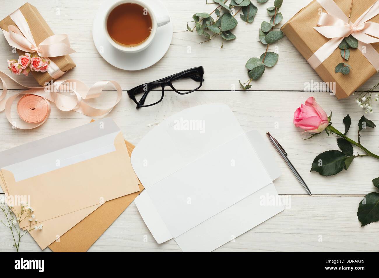 Creative Workspace With Gifts, Flowers, Tea, and Stationery Arranged Neatly on a Wooden Table Stock Photo