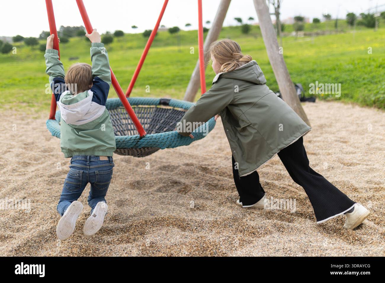 Children playing on nest swing in park Stock Photo