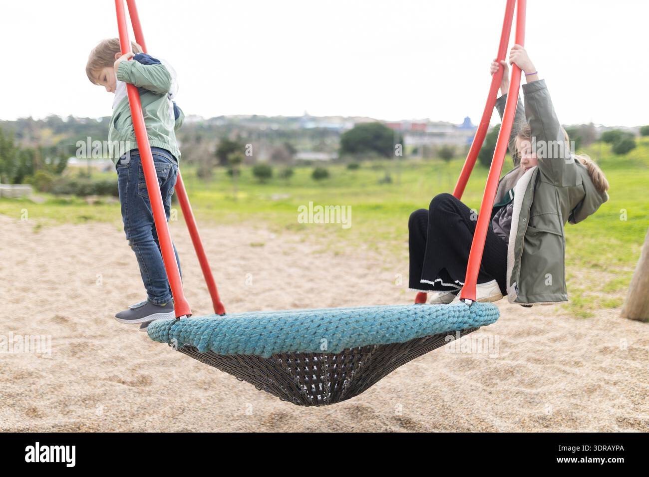 Children playing on nest swing at playground park Stock Photo